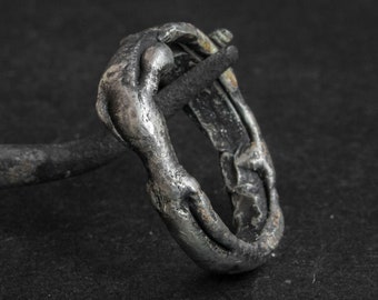 May include: A silver ring with a textured, organic design. The ring is made of metal and has a worn, antique look.