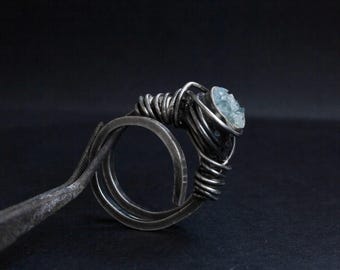 May include: A silver ring with a wire-wrapped design and a light blue gemstone.