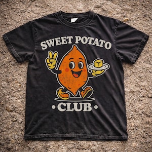 May include: Black t-shirt featuring a cartoon sweet potato character with a peace sign and a pat of butter. The text "SWEET POTATO CLUB" is printed above and below the character in white.