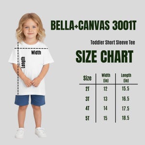 Puede incluir: Un ni&ntilde;o lleva una camiseta blanca de manga corta para ni&ntilde;os peque&ntilde;os y pantalones cortos azules. La imagen incluye una tabla de tallas con medidas en pulgadas para las tallas 2T a 5T. Tambi&eacute;n se ve el texto "BELLA+CANVAS 3001T" y "SIZE CHART".