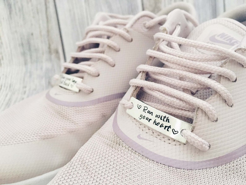 May include: A pair of light pink trainers with white laces and a silver charm on the laces that reads "Run with your heart".