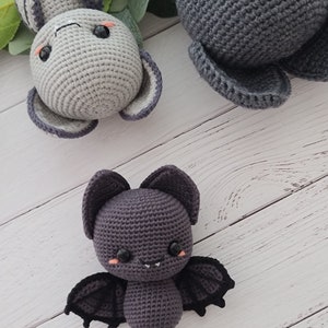 Puede incluir: Tres animales de peluche tejidos a crochet: un murci&eacute;lago gris con alas negras, un conejito gris con mejillas rosadas y un elefante gris con mejillas rosadas.
