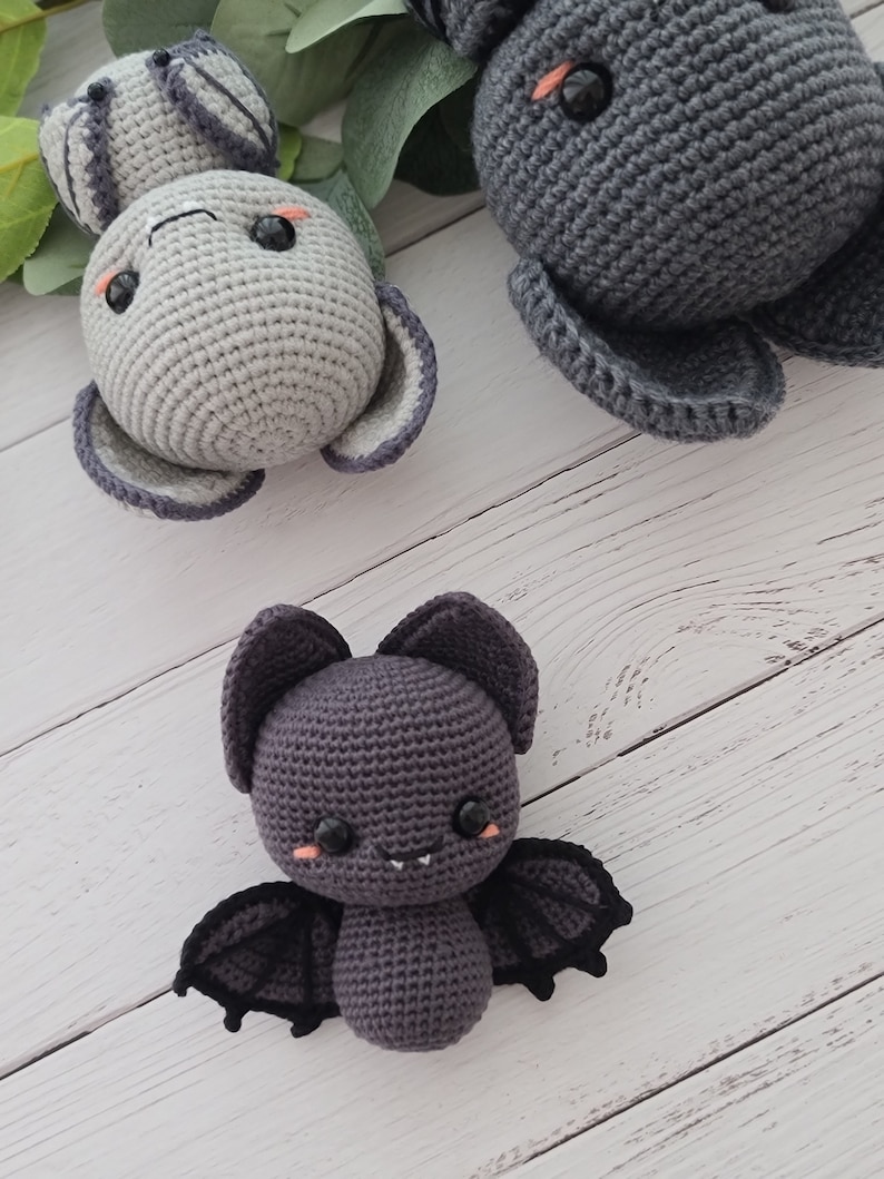 Puede incluir: Tres animales de peluche tejidos a crochet: un murci&eacute;lago gris con alas negras, un conejito gris con mejillas rosadas y un elefante gris con mejillas rosadas.