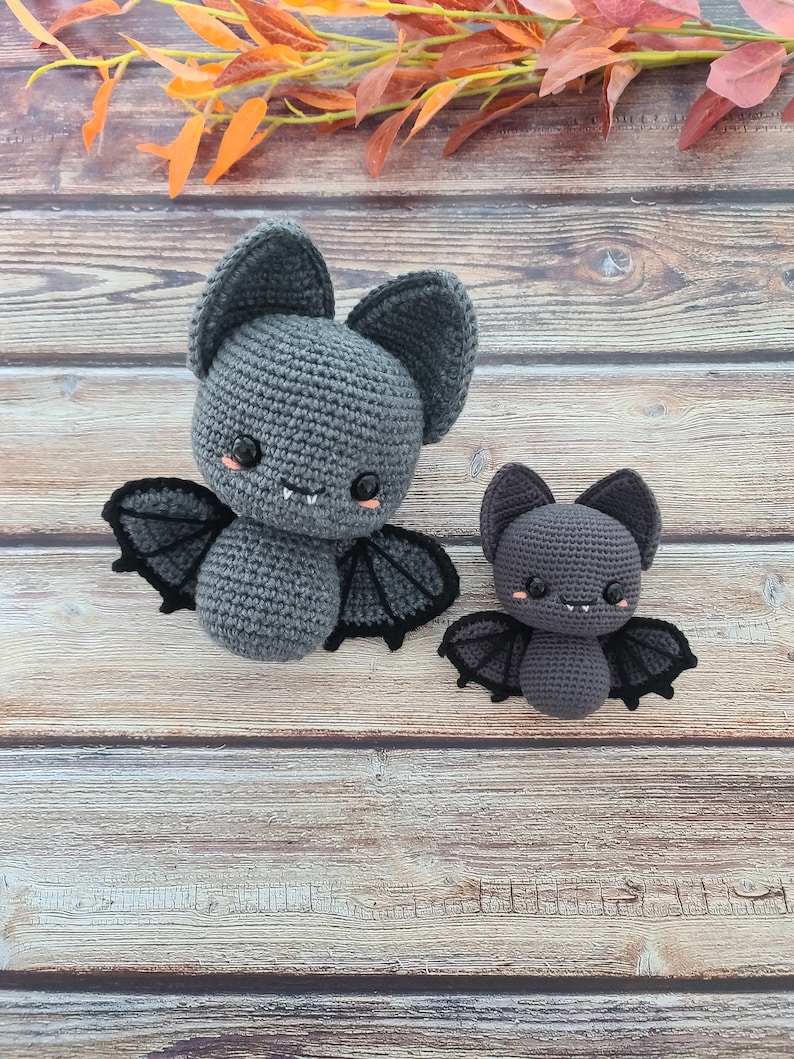 Puede incluir: Dos murci&eacute;lagos de crochet grises con ojos negros y alas. El murci&eacute;lago m&aacute;s grande tiene una sonrisa de dientes y es ligeramente m&aacute;s grande que el m&aacute;s peque&ntilde;o.