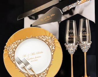 Puede incluir: Juego de cuchillo y servidor para pastel de bodas dorado con adornos de cristal, dos copas de champán con borde dorado con adornos de cristal y un plato de servicio dorado con un plato blanco y dos tenedores. Los platos y las copas están personalizados con los nombres "Mr. & Mrs. Solomon" y "Mr. & Mrs. Bethen" y sus fechas de boda.