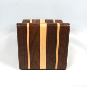 May include: A wooden block with a rectangular shape. The block features a vertical design with alternating stripes of dark brown and light tan wood. The wood grain is visible, and the block has a smooth, polished finish.