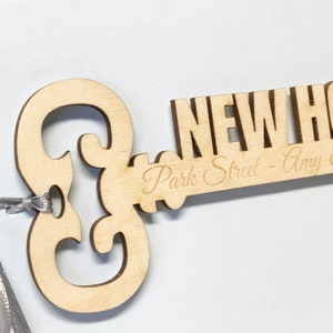 wooden key shape engraved with your special message and names of the new home owners attached to a card as a housewarming keepsake gift