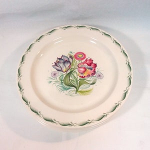 May include: A white ceramic dinner plate with a green border and a floral design featuring pink, purple, and yellow tulips.