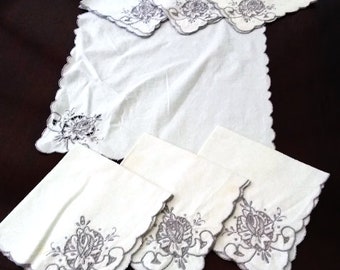 May include: Set of white linen napkins with embroidered grey floral designs. The napkins have scalloped edges and are perfect for formal dining.