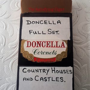 May include: A vintage box of Doncella Coronet cigars, labeled "Full Set" and "Country Houses and Castles". The box is brown with gold lettering and a black label with a gold design.