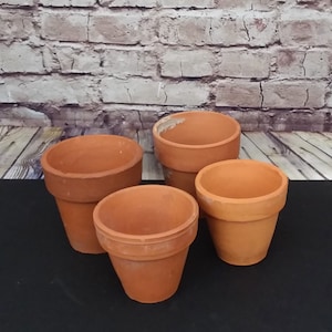 May include: Four terracotta flower pots of varying sizes. The pots are unglazed and have a natural brown colour.