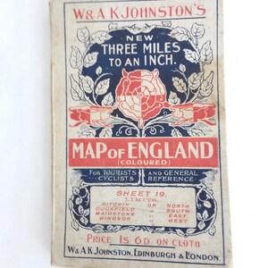 May include: A vintage map of England, printed on cloth, with a rose design and the text "W&A KJohnston's New Three Miles to an Inch. Map of England (Coloured) For Tourists and General Cyclists Reference. Sheet 19. Limits. Hitchin on North, Cuckfield on South, Maidstone on East, Windsor on West. Price is 6d on cloth. W&AK Johnston, Edinburgh & London."