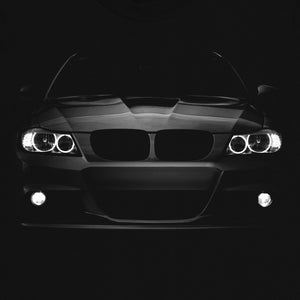 Op de afbeelding: Zwart T-shirt met een vooraanzicht van een zwarte auto. De koplampen en grille van de auto zijn zichtbaar.