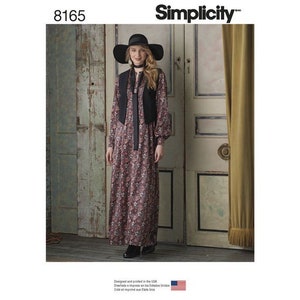 May include: A woman wearing a long floral dress, black vest, and wide-brimmed hat. The dress has long sleeves and a floral pattern in shades of red, pink, and green. The vest is black, and the hat is also black. The Simplicity logo is visible.