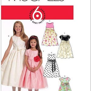 May include: McCall's pattern for girls' dresses. The image shows two girls wearing dresses, with several dress designs displayed. The dresses include a white dress, a pink dress, and dresses with floral and polka dot patterns. The McCall's logo is at the top.