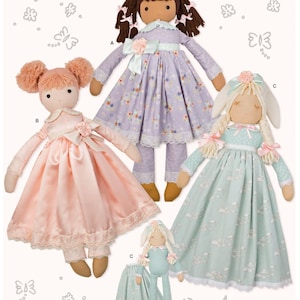 May include: Three handmade fabric dolls with different hair colors and outfits. The doll on the left is wearing a pink dress with lace trim, the doll in the center is wearing a purple dress with floral print, and the doll on the right is wearing a light blue dress with a cloud print.