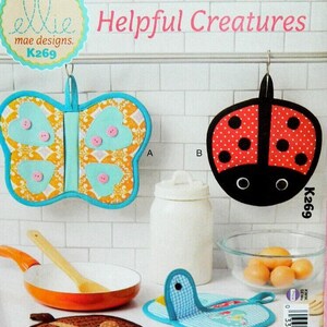 May include: A collection of colorful kitchen accessories, including a butterfly-shaped pot holder, a ladybug-themed pot holder, and a giraffe-patterned trivet. The image also features a small frying pan, a wooden spoon, and a glass bowl with eggs.