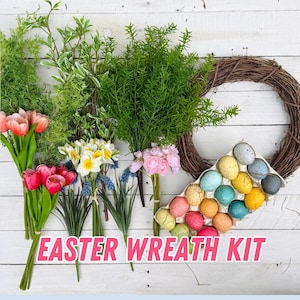 May include: An Easter wreath kit with a variety of faux flowers, greenery, and speckled eggs. The kit includes a grapevine wreath, tulips, daffodils, and other floral elements. The words "EASTER WREATH KIT" are displayed in pink.