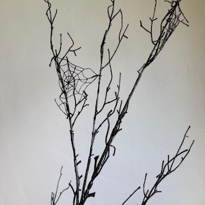 May include: A set of bare, black-painted branches featuring thin, intricate, black spider web designs attached to the twigs. The branches are slender and multi-pronged, extending upward with a dark, matte finish throughout the structure.