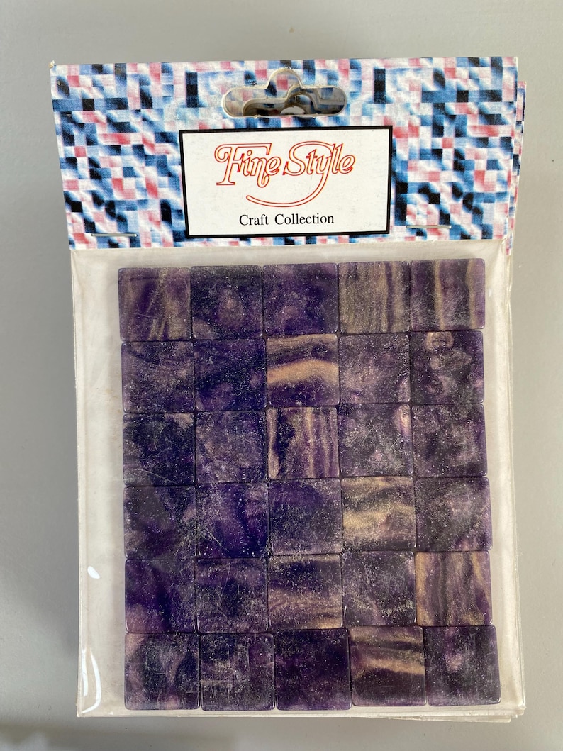 May include: A package of purple and white mosaic tiles. The package has a label that says "Fine Style Craft Collection".
