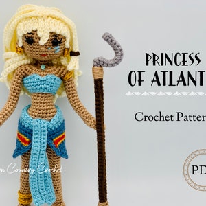 May include: Crochet pattern for a Princess of Atlantis doll. The doll is made of brown, blue, and white yarn and is holding a brown staff with a gray hook. The pattern is available as a PDF download.  "Princess of Atlantis" and "Crochet Pattern" are written in black text on a gray background.