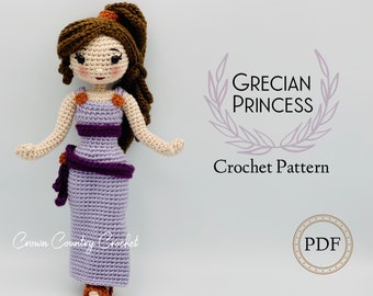 May include: Crochet pattern for a Grecian princess doll. The doll is wearing a purple dress with a brown sash and has brown hair. The pattern is available as a PDF download.