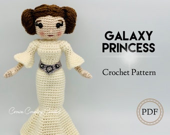 May include: A handmade crochet doll in a cream-colored gown, resembling a princess. The doll has brown yarn hair styled in buns, and a silver belt. The text "GALAXY PRINCESS Crochet Pattern" is displayed on the right side of the image.