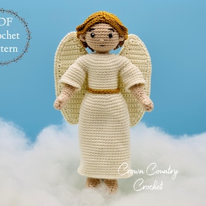 May include: A crocheted angel doll with a cream-colored dress, wings, and halo. The doll has a gold-colored belt and hair. The text "PDF Crochet Pattern" is in a circle on the upper left. The text "Crown Country Crochet" is on the lower right.