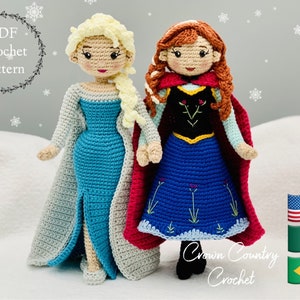 Può includere: Schema di uncinetto per due bambole, una con un vestito blu e bianco e una treccia bionda, e l'altra con un mantello rosso e un vestito blu e nero. Le bambole sono in piedi su una superficie bianca con fiocchi di neve sullo sfondo. Il testo "Crown Country Crochet" è visibile nella parte inferiore dell'immagine.