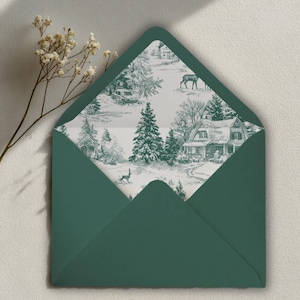 May include: A dark green envelope with a winter scene design on the inside. The design features a house, trees, and deer in a black and white illustration. The envelope is open, revealing the detailed pattern.