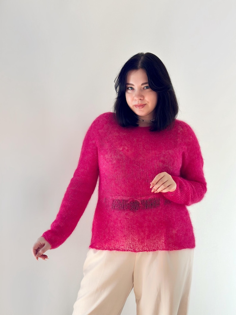 May include: A woman wearing a pink fluffy sweater and beige trousers.