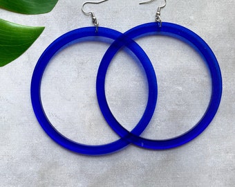 May include: A pair of large, blue, acrylic hoop earrings with silver hooks.