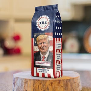May include: A bag of Republican Coffee Company Trump Roast coffee featuring a portrait of Donald Trump against an American flag background. The packaging is red, white, and blue with stars and stripes, and includes the text Net Wt 12oz (340g).