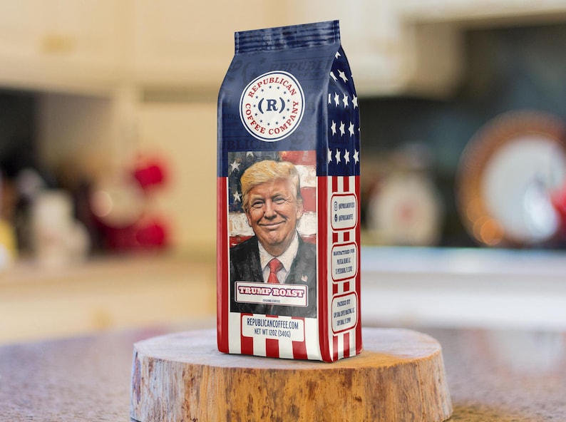 May include: A bag of Republican Coffee Company Trump Roast coffee featuring a portrait of Donald Trump against an American flag background. The packaging is red, white, and blue with stars and stripes, and includes the text Net Wt 12oz (340g).