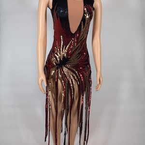 May include: A sleeveless sequined dress with a plunging neckline. The dress is red, gold, and black with a fringe hem.