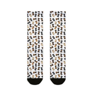 May include: A pair of socks with a repeating pattern of cartoon dachshund dogs in various colors, including black, brown, and tan. The socks have black toes and heels. The background is white.