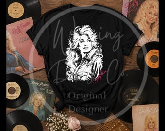 May include: A black short-sleeved t-shirt featuring a white graphic illustration of Dolly Parton with long wavy hair and a collared shirt. The name Dolly Parton is printed in pink script below the illustration on the center of the chest.