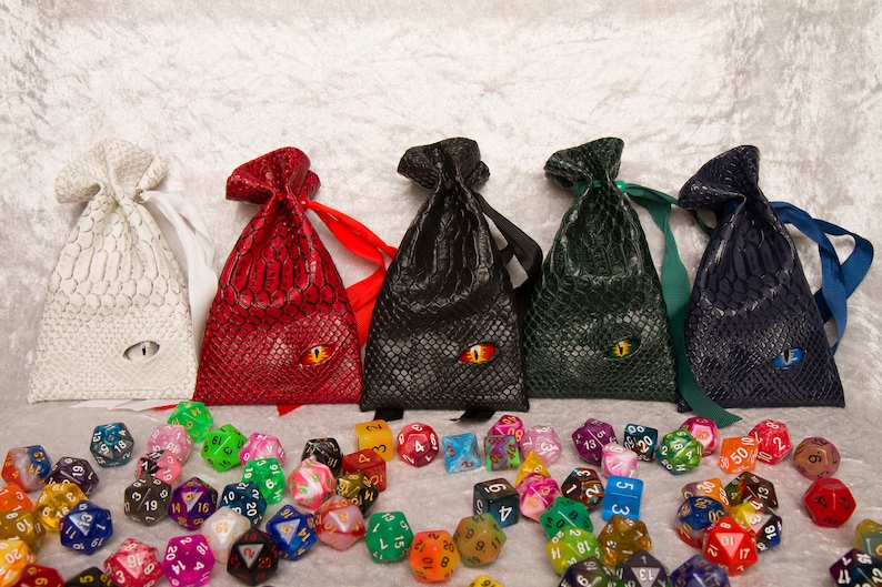 A selection of pocket-sized dice bags made of faux leather with a dragon style texture and an eyeball embedded in the front - available in white, red, black, green and blue.