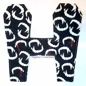 May include: A pair of black fabric coffin-shaped Halloween decorations with a white and red vampire teeth pattern. The text "Teyha's Creations" is printed on the fabric.