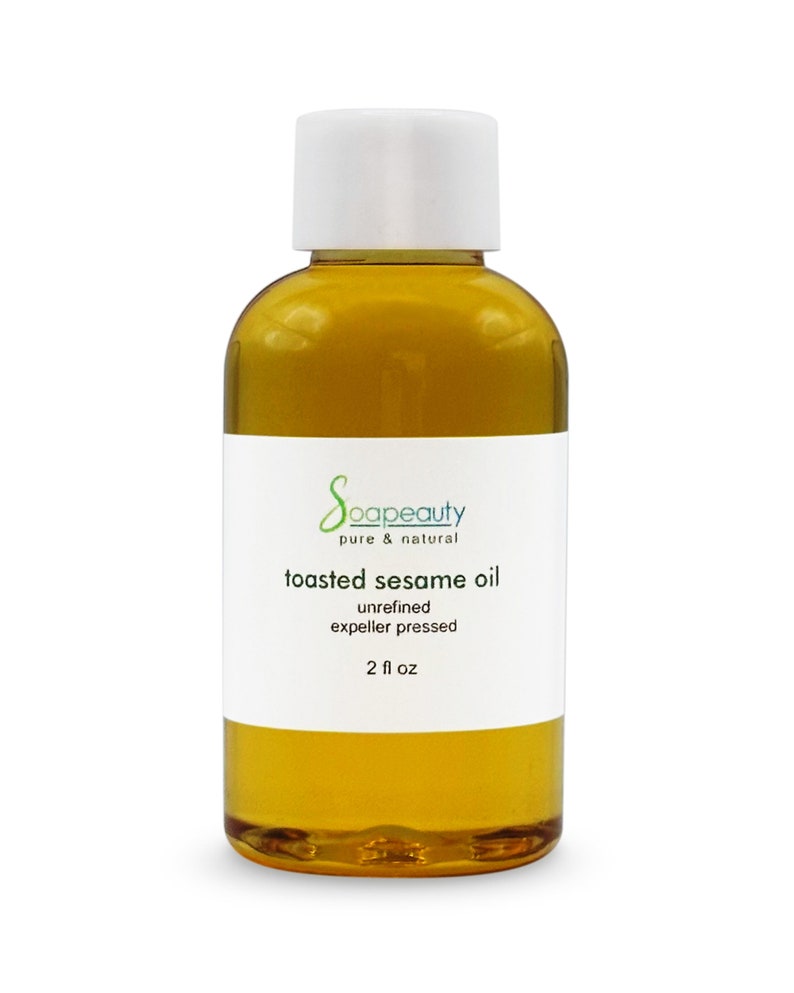 May include: A clear glass bottle with a white cap filled with toasted sesame oil. The label reads "soapeaty pure & natural toasted sesame oil unrefined expeller pressed 2 fl oz".
