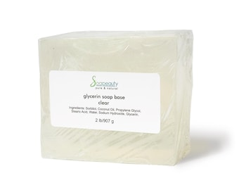 May include: A clear glycerin soap base in a rectangular shape, wrapped in plastic. The label reads "Soapeauty pure & natural glycerin soap base clear" and lists the ingredients: Sorbitol, Coconut Oil, Propylene Glycol, Stearic Acid, Water, Sodium Hydroxide, Glycerin. The label also states "2 lb/907 g".