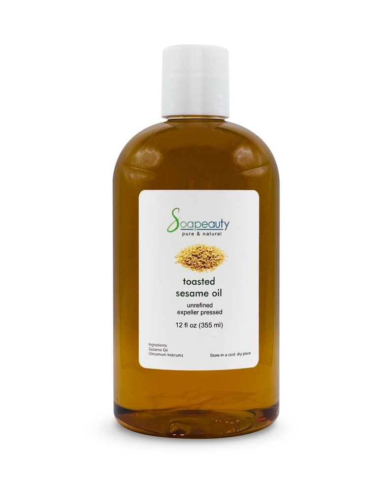 May include: A clear glass bottle with a white cap filled with toasted sesame oil. The label reads "Soapeauty pure & natural toasted sesame oil unrefined expeller pressed 12 fl oz (355 ml) Ingredients: Sesame Oil (Sesamum Indicum) Store in a cool dry place"