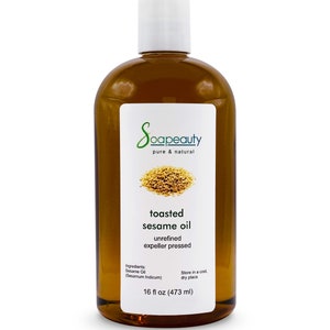 May include: A clear glass bottle with a white cap filled with toasted sesame oil. The label reads "Soapeauty pure & natural toasted sesame oil unrefined expeller pressed Ingredients: Sesame Oil (Sesamum Indicum) Store in a cool dry place 16 fl oz (473 ml)"