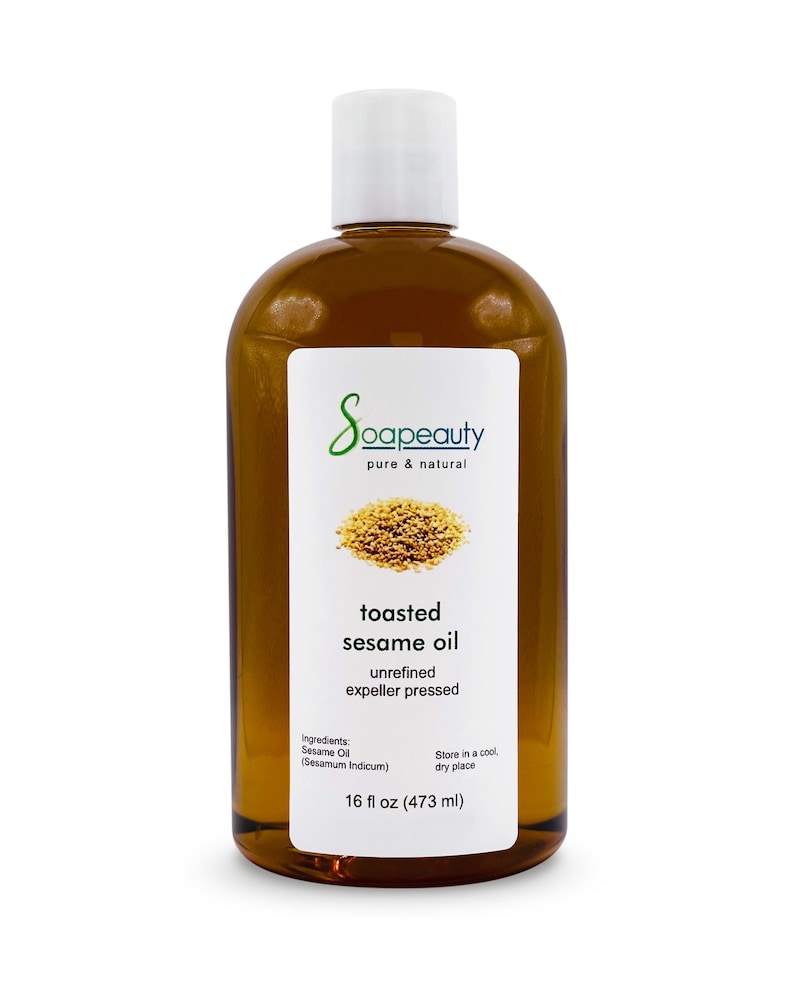 May include: A clear glass bottle with a white cap filled with toasted sesame oil. The label reads "Soapeauty pure & natural toasted sesame oil unrefined expeller pressed Ingredients: Sesame Oil (Sesamum Indicum) Store in a cool dry place 16 fl oz (473 ml)"