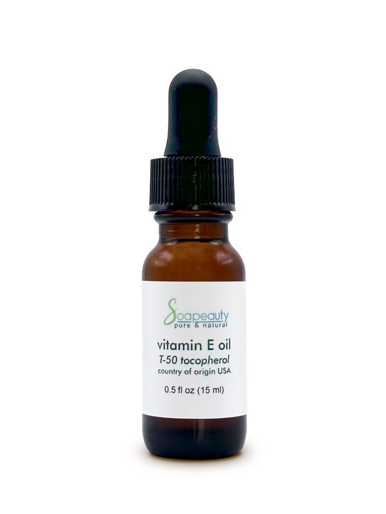 May include: A brown glass bottle with a black dropper top. The bottle is labeled "Soapeauty pure & natural vitamin E oil T-50 tocopherol country of origin USA 0.5 fl oz (15 ml)"
