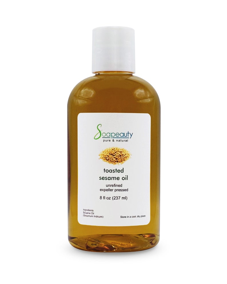 May include: A clear glass bottle with a white cap filled with toasted sesame oil. The label reads "Soapeauty pure & natural toasted sesame oil unrefined expeller pressed 8 fl oz (237 ml) Ingredients: Sesame Oil (Sesamum indicum) Store in a cool, dry place."