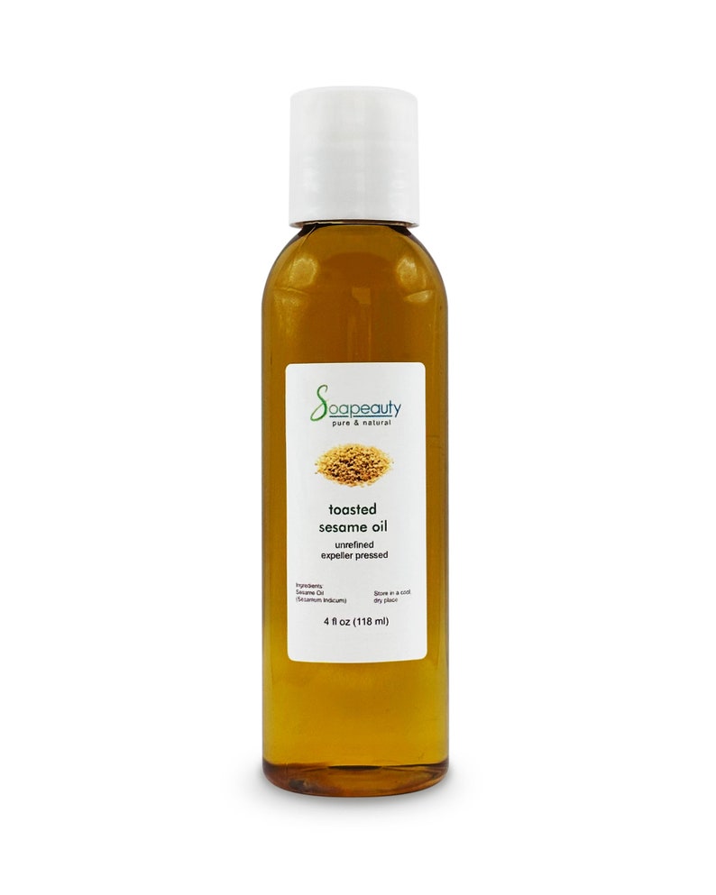 May include: A clear glass bottle with a white cap filled with toasted sesame oil. The label reads "Soapeauty pure & natural toasted sesame oil unrefined expeller pressed" and lists the ingredients as "Sesame Oil (Sesamum indicum)". The bottle contains 4 fluid ounces (118 ml) of oil.