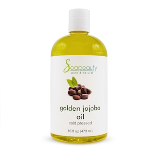 May include: A bottle of golden jojoba oil from Soapeauty. The label features the brand name, a graphic of jojoba beans and leaves, and the text "golden jojoba oil, cold pressed, 16 fl oz (473 ml)." The bottle has a white cap.