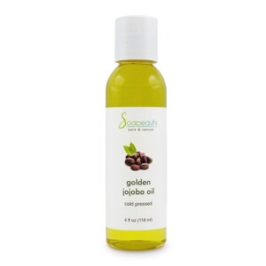 May include: A clear glass bottle filled with golden jojoba oil. The label reads "Soapeauty pure & natural" and "golden jojoba oil cold pressed". The bottle contains 4 fl oz (118 ml) of oil. The label also features an illustration of jojoba beans and leaves.