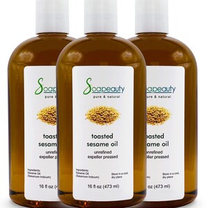 May include: Three 16-ounce bottles of toasted sesame oil, unrefined and expeller pressed. The bottles are amber glass with white labels and a white cap. The label says "Soapeauty pure & natural" and includes the ingredients, "Sesame Oil (Sesamum Indicum)".